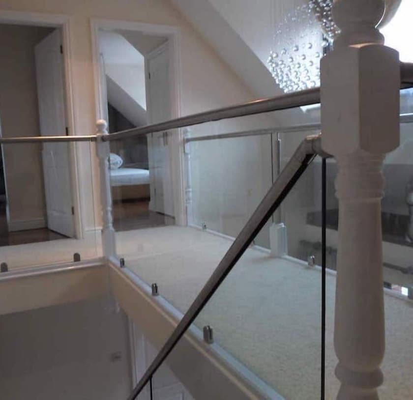 Glass balustrade with wooden posts and stainless steel handrails around a staircase