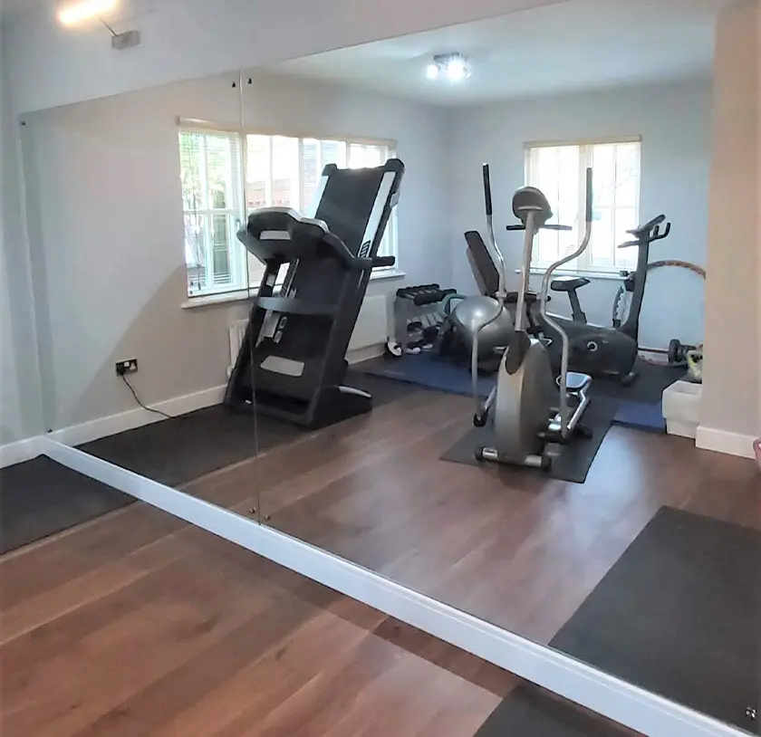 Wall length large custom cut mirror reflecting gym equipment