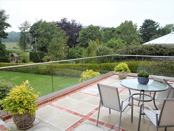 Glass balustrade with stainless steel handrail on a balcony overlooking a garden