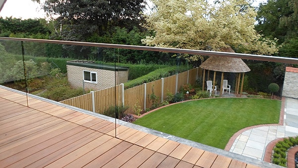 Glass balustrade with stainless steel handrail on a balcony overlooking a garden