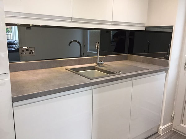 Splashback mirror above kitchen countertop and sink