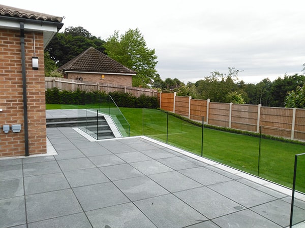 Frameless glass balustrade around a patio ang garden steps